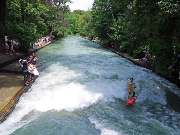 Münih, Almanya - 23 Temmuz 2016 - genç sörf, izlerken, Eisbach, Isar Nehri yan kol küçük bir insan yapımı nehir, Englischer Garten veya Central Park olarak bilinen parkın içinden akan turist ise su adam