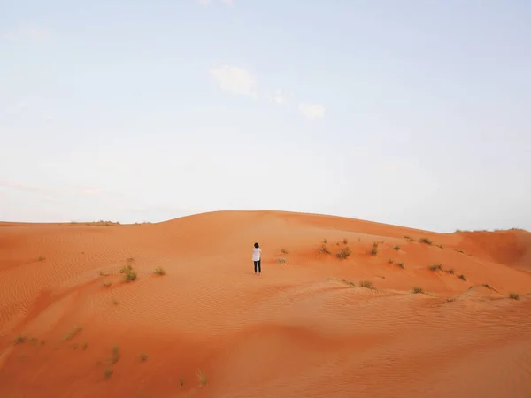 Solo asian female traveler in white, standing alone, surrounded by large sand dunes of Wahiba, a large desert area four hours drive from Muscat, the capital of the Sultanate of Oman. — Stock Photo, Image