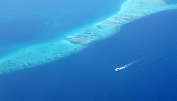 관광 페리 보트 산호초 장벽 몰디브의 섬 중 하나에 따라 실행. 물이 깊고 푸른 색상에 아름 답게 하 고 그래서 크리스탈 분명 우리가 명확 하 게 수 중 산호초를 볼 수 있습니다.. — 스톡 사진