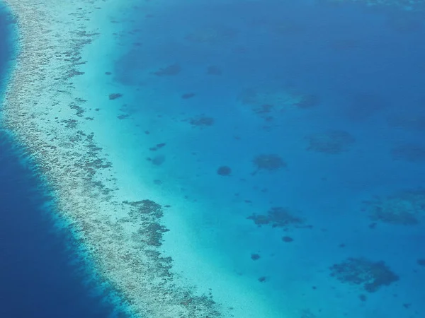 Vista aérea de um atol nas Maldivas com recifes de corais subaquáticos vistos através de água azul clara do mar. Maldivas é um país insular tropical no Oceano Índico composto por mais de mil ilhas . Fotografias De Stock Royalty-Free