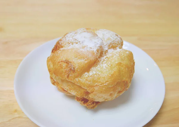 Bütün ev yapımı Japon choux krem puf küçük beyaz tabak içinde ahşap bir masa üzerine krema ile — Stok fotoğraf