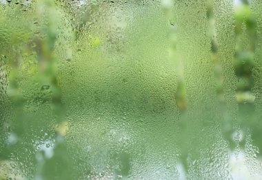 Su damlacıkları üzerinde şeffaf cam pencere odak ağaçların yeşil arka plan ile ön plan temizleyin ve havuza su