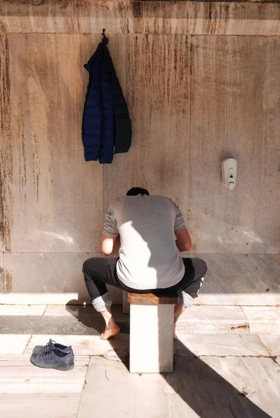 Muslim believer doing ablution process which is washing hands, mouth, nostrils, arms, head and feet with water (Wudu) to make himself clean before entering an Islamic Mosque to pray
