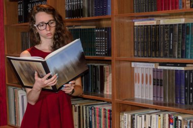 Konsantre kız okuma bir kitap kütüphane