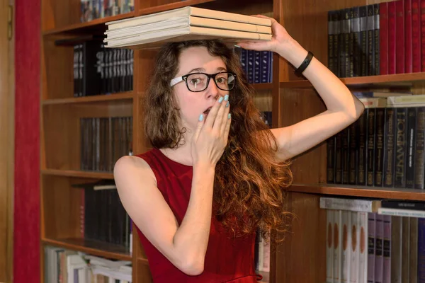 Kafa ve yawns kitap tutan gözlük ile kız.