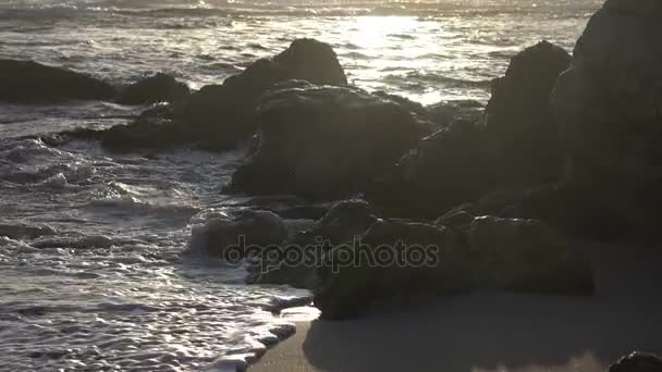 Olas de cámara lenta que se estrellan entre rocas doradas — Vídeo de stock