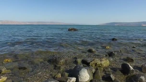 Caminando sobre rocas en la orilla del mar de Galilea en Israel — Vídeos de Stock