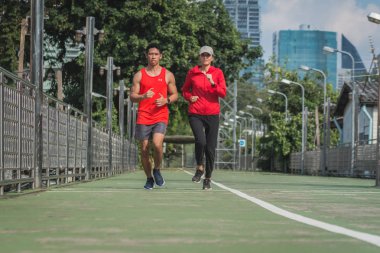 Şehir parkında koşu yolunda koşan genç bir çift., 