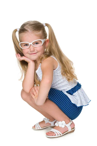 Little girl in glasses is sitting against the white — Stock Photo, Image