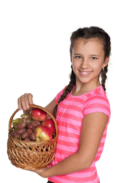 Jong meisje houdt een mandje met groenten — Stockfoto