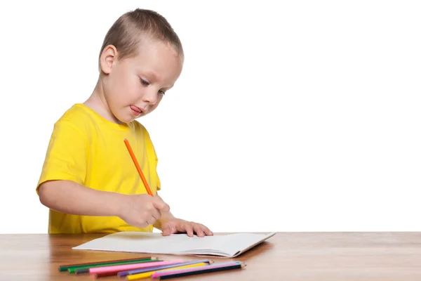 Kleiner Junge sitzt am Schreibtisch und schreibt — Stockfoto