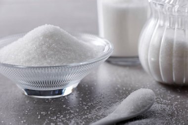 Kapalı kâse ve kaşık. Taş masa arkasında beyaz kum var.