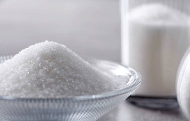 Kapalı kâse ve kaşık. Taş masa arkasında beyaz kum var.