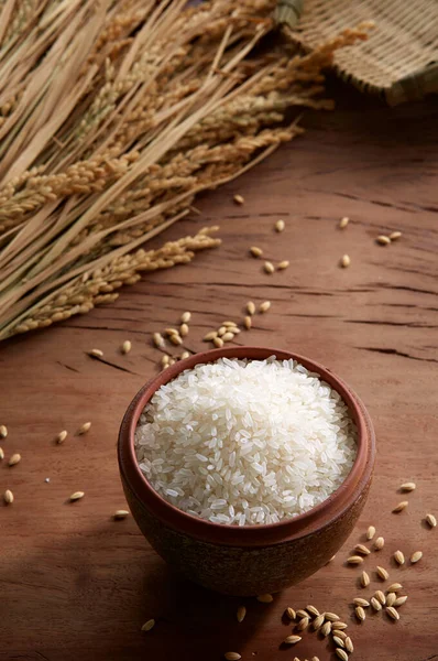 Raw rice in a pot on wooden background