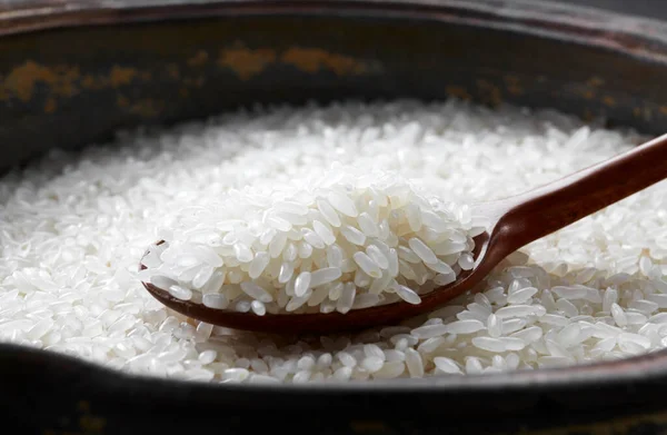 米を背景にした木のスプーンでご飯 — ストック写真