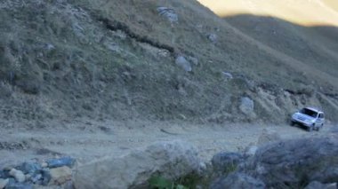 Kayalık bir dağ yolunda arazi aracı sürüyor.
