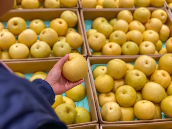 Женщина собирает свежую желтоватую грушу в продуктовом магазине — стоковое фото