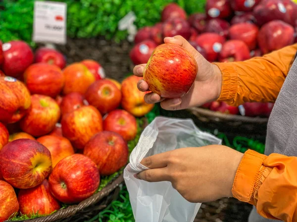 Ανθρώπινο χέρι μαζεύοντας ένα μήλο και χρησιμοποιώντας βιο-πλαστική σακούλα — Φωτογραφία Αρχείου