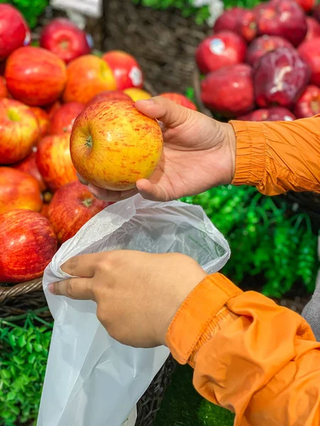 Человек использует биопластическую сумку при покупке яблок в продуктовом магазине — стоковое фото