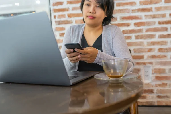 Mujer asiática usando portátil y teléfono inteligente en la cafetería — Foto de Stock