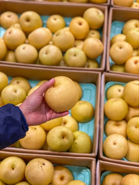 Человеческая рука держит желтую свежую грушу в магазине фруктов — стоковое фото