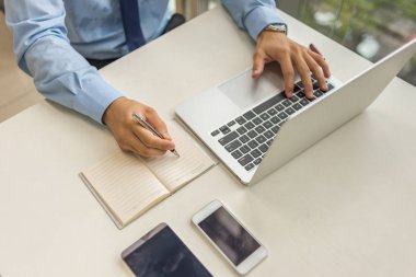 Dizüstü bilgisayarda çalışan ve notlar yazma iş adamı