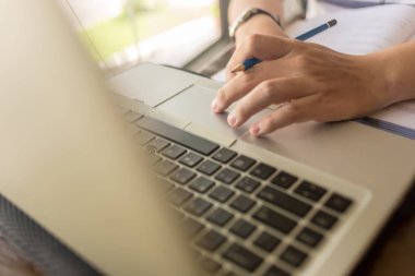 Man using laptop touchpad while holding pen