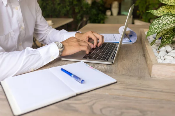 Primer plano de la foto del hombre de negocios que escribe el ordenador portátil al lado del cuaderno — Foto de Stock