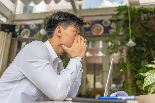 Frustrated Asian businessman sitting with laptop at coffee shop — 图库照片