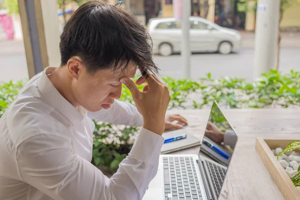 沮丧的年轻亚洲商人带着笔记本电脑坐在自助餐厅里 — 图库照片