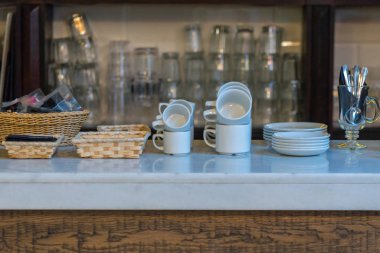 Bardaklar ve kupalar paslanmaz tezgahta düzenli bir düzende.