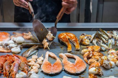 Şef, restoranların mutfağında spatula kızartıcı çeşit deniz ürünleri kullanıyor.