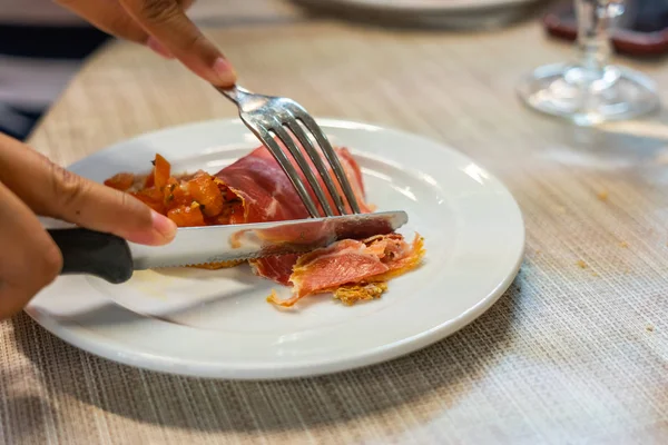 Människa som använder kniv och gaffel när hon äter saltad köttskiva — Stockfoto