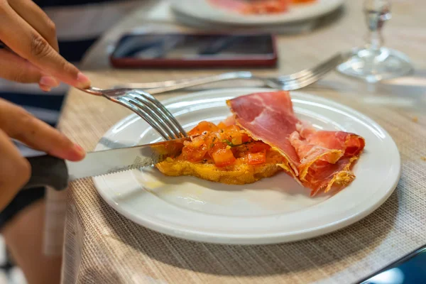 Människa som använder kniv och gaffel när hon äter middag med bacon — Stockfoto