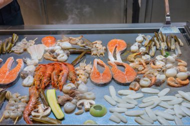 Açık büfedeki büyük ızgara tavasında çeşitli deniz ürünleri.