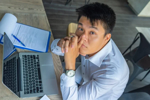 Joven hombre de negocios asiático sentado con portátil y papeleo en la oficina — Foto de Stock