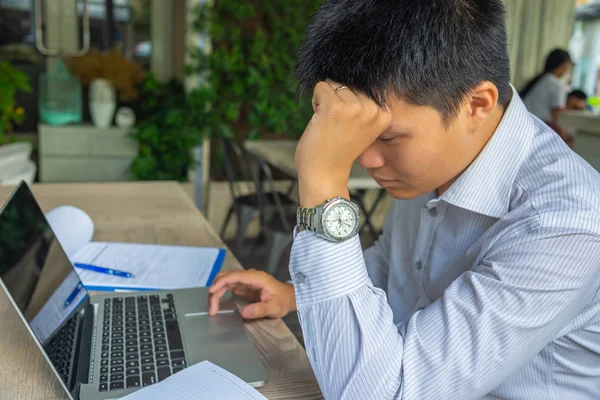 Uomo d'affari stanco seduto con laptop e scartoffie sul posto di lavoro — Foto Stock