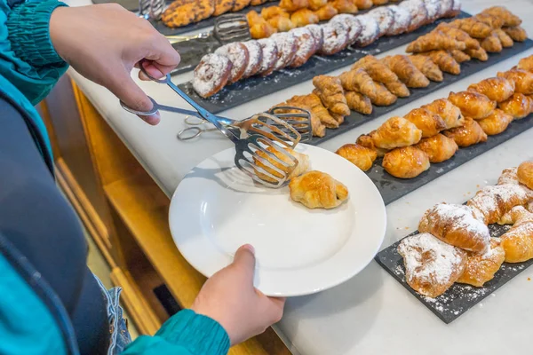 Vrouw kiest croissants bij banketbakker in buffetrestaurant — Stockfoto