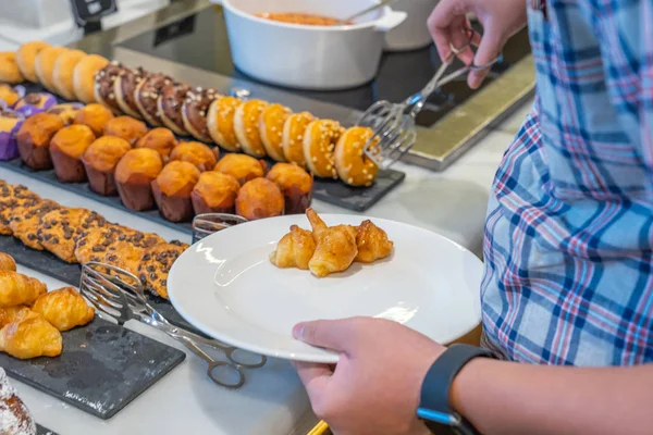 Aziatisch man plukken donut door tang bij gebak teller — Stockfoto