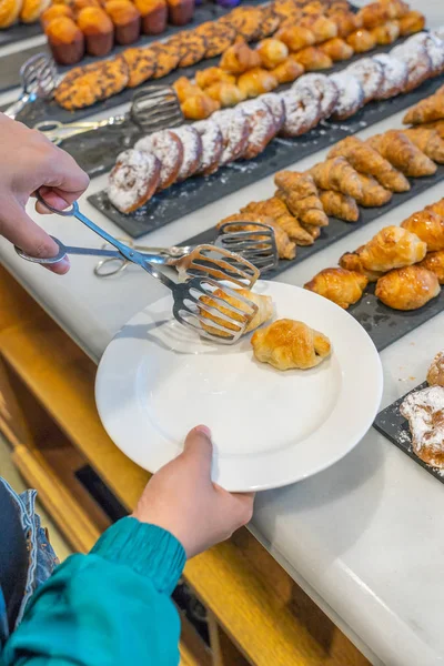 Verticale foto van de vrouw met behulp van tang en het selecteren van gebak croissant — Stockfoto