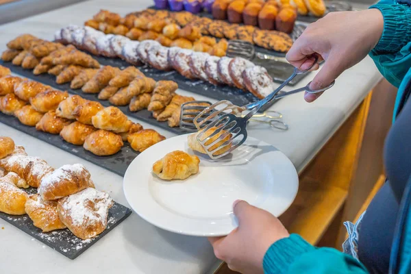 Menselijke hand plukken croissant gebak in schotel bij buffetmaaltijd — Stockfoto