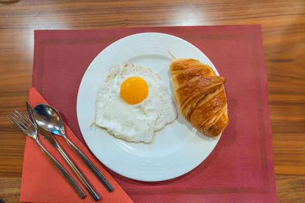 Croissant hinchado y huevo soleado en plato blanco para el desayuno — Foto de Stock