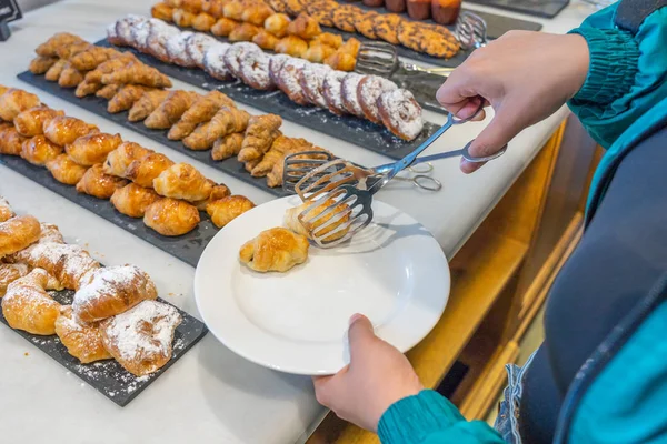 Vrouw die botercroissant selecteert bij banketbakker in buffetrestaurant — Stockfoto