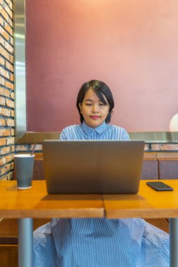 Ortak çalışma alanında dizüstü bilgisayarda çalışan genç bir kadın serbest yazar.