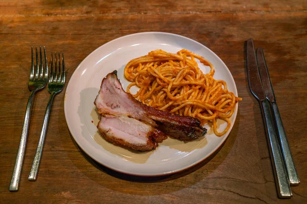 Вкусная паста и жареные свиные ребрышки на деревенском столе — стоковое фото