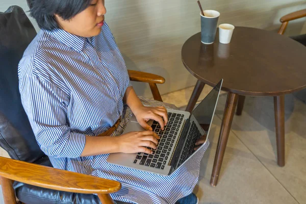 Asiática mujer de negocios sentado en sillón y el uso de ordenador portátil — Foto de Stock
