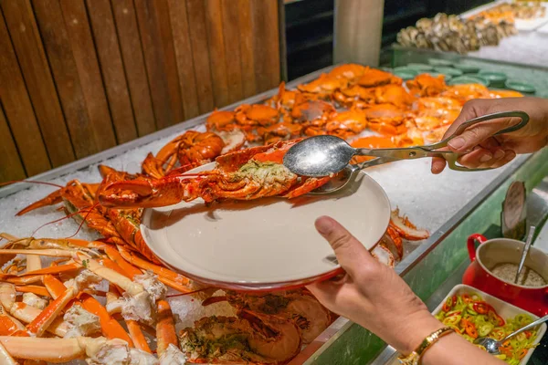 Vrouw hand met behulp van tangen om kreeft te plukken bij zeevruchten buffet — Stockfoto