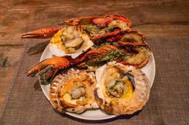 Kaba ahşap masada ızgara ıstakoz ve istiridye.