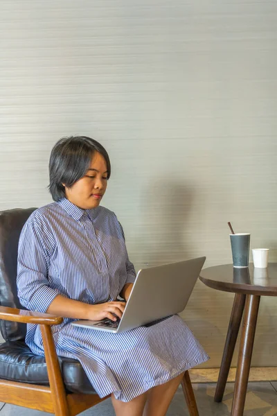 Asiática pelo corto freelancer femenino utilizando ordenador portátil en la mesa de café — Foto de Stock