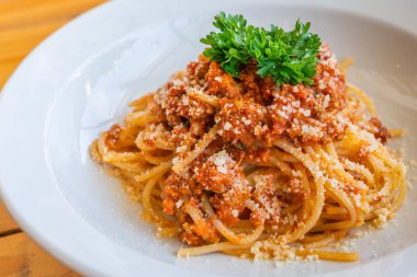 Maydanoz ve peynirle süslenmiş kıymalı spagetti.